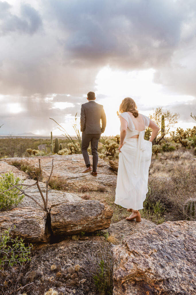 Bride and groom walking through desert vegetation at Saguaro National Park in Tucson