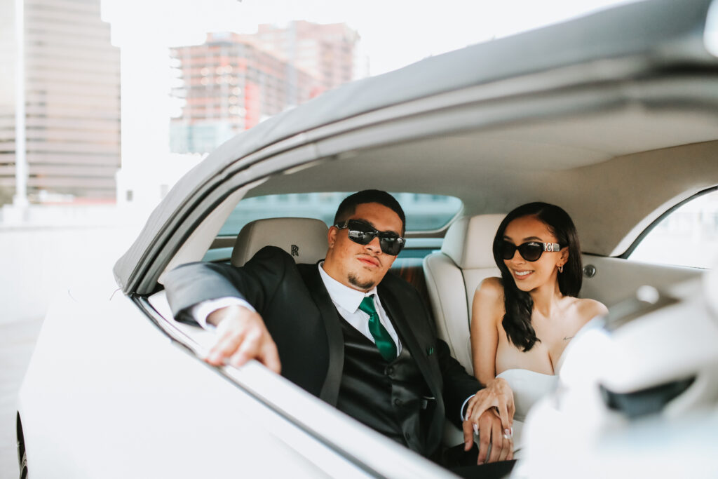 bride and groom pose in back of rolls royce