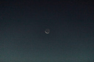 The moon visible above the desert canyon during sunrise elopement