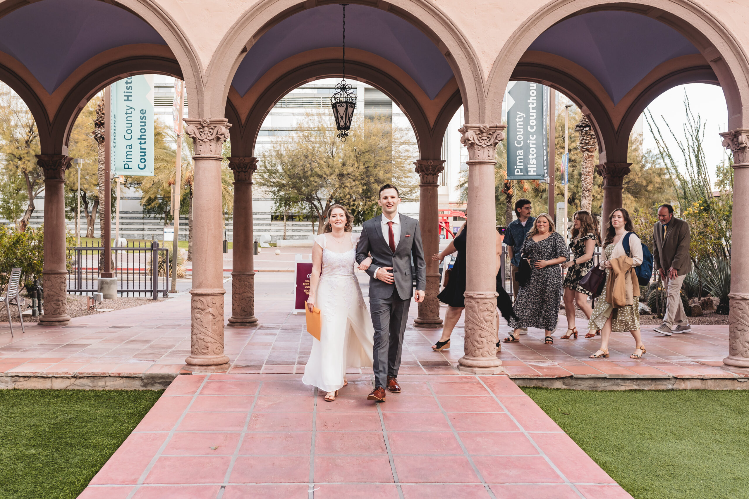 Bride and groom walking together with guests at Pima County Historic Courthouse