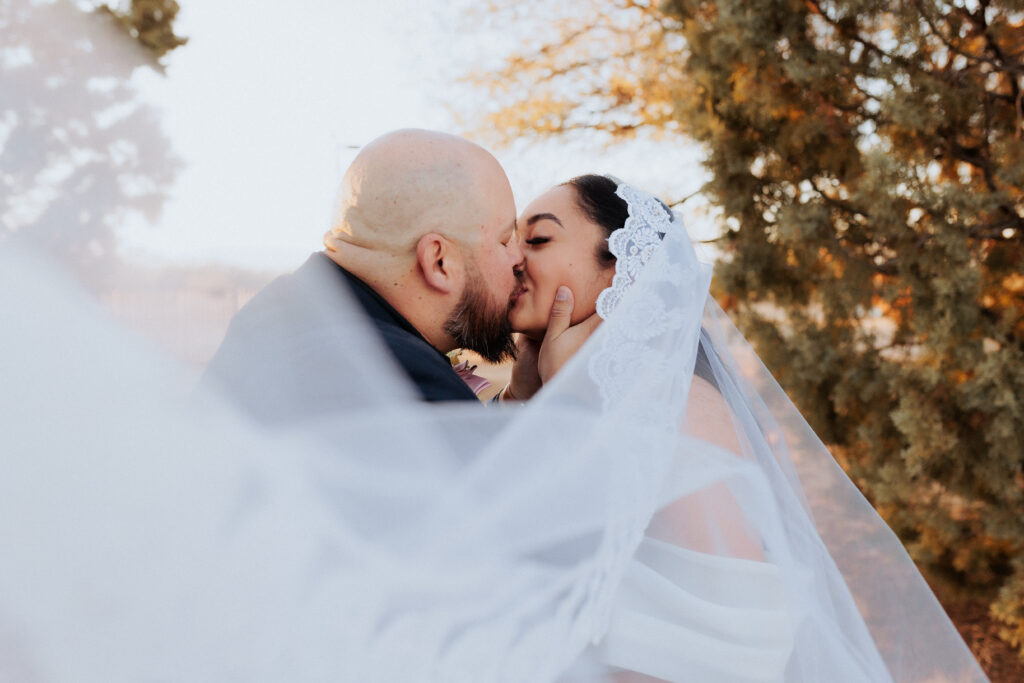 bride and groom kissing with veil blowing in willcox arizona