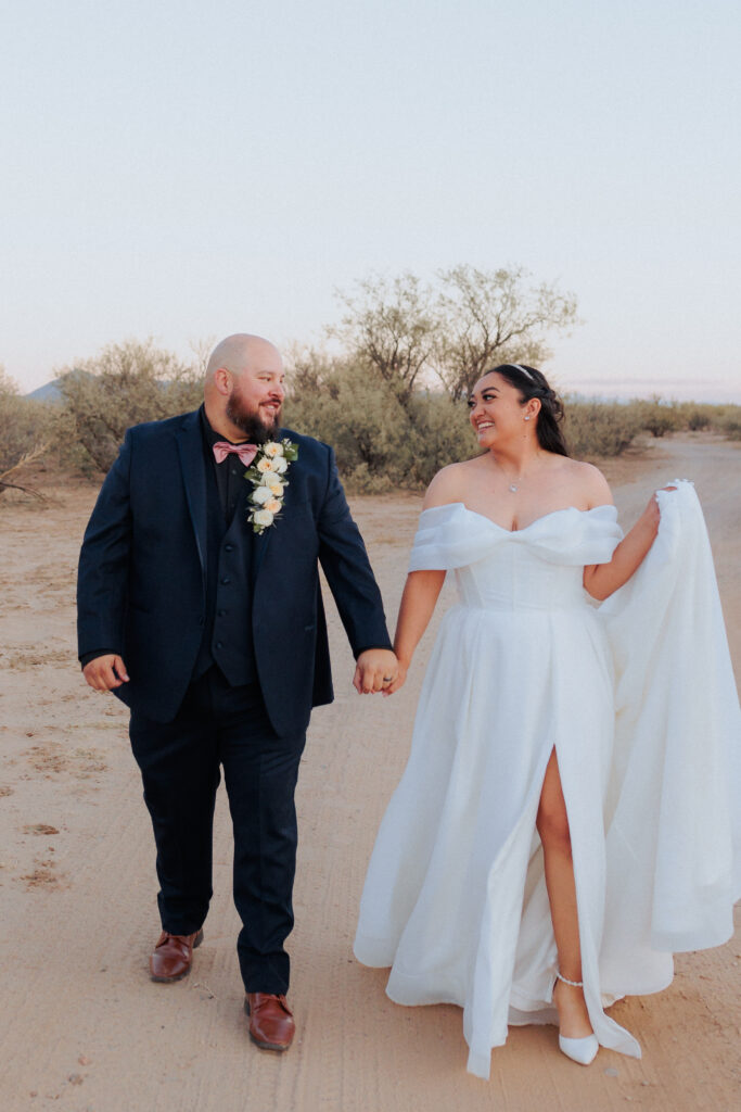 Bride and groom holding hands at desert venue
