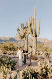 Wide shot of a wedding ceremony at Sabino Canyon in Tucson, Arizona, featuring the couple standing before a scenic desert landscape after getting ready at Westin La Paloma.
