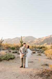 A romantic wide shot of the couple embracing in the desert landscape of Sabino Canyon at sunset for their bridal portraits.