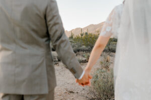 up close of couples hands with saguaros in the background