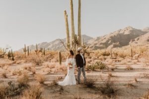 Couple standing close together with desert scenery around them