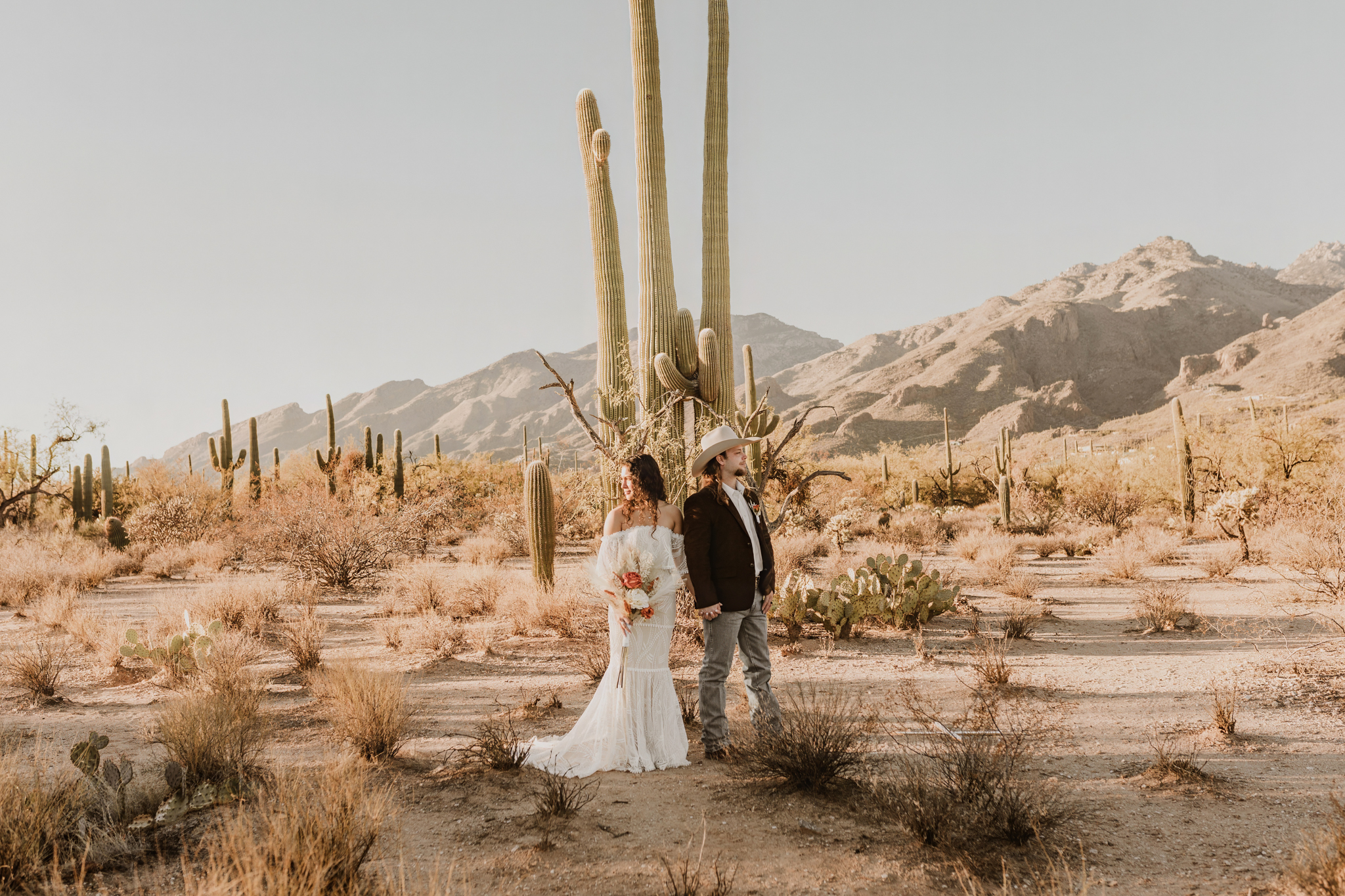 Couple standing close together with desert scenery around them