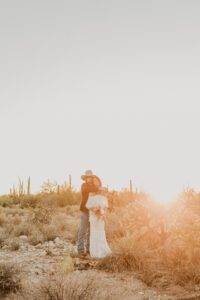 groom holding his bride from behind during golden hour hugging her