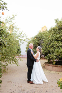 bride and groom posing among orange trees during bridal session