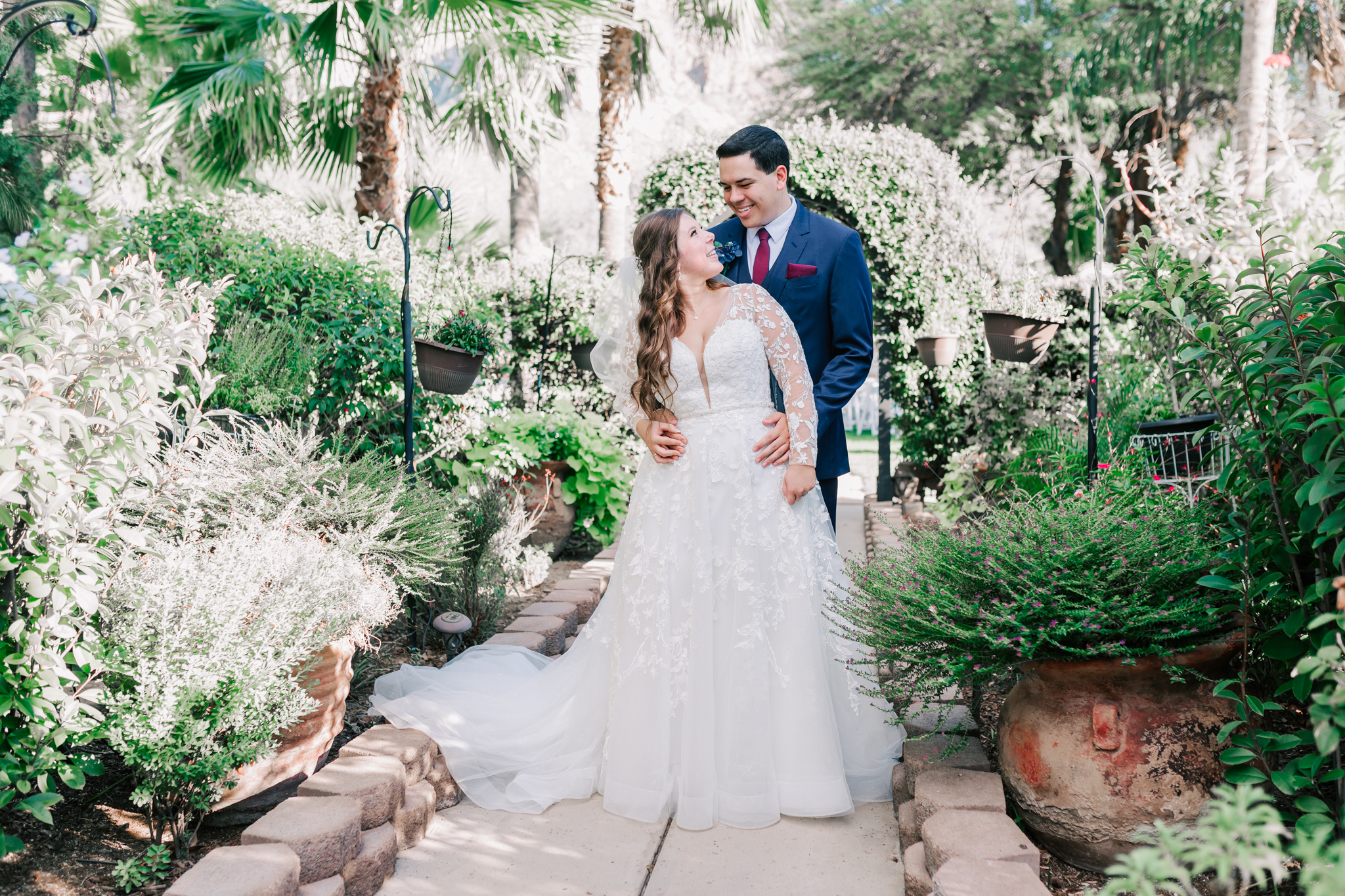groom standing behind bride while bride looks up at him in a garden walkway at buttes at reflections tucson az wedding venue