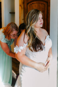Close-up of a bride wearing an off-the-shoulder lace wedding gown while getting ready.