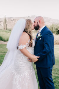 Bride and groom kissing outdoors with mountains behind them