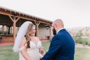 Bride laughing while holding the groom's hands outdoors near the reception pavilion