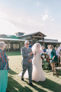 Bride's father walking her toward the ceremony in front of the Barn atTanque Verde Ranch