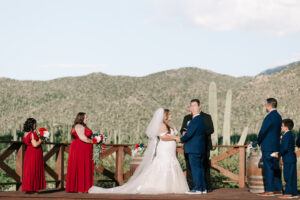 Bride and groom holding hands during the ceremony, officiant and groomsmen standing beside them