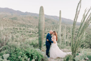 Bride and groom sharing a quiet moment among tall saguaros in the desert