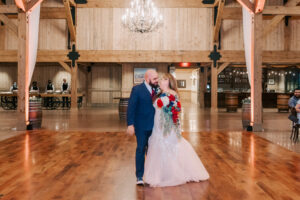 Bride and groom walking hand in hand across the dance floor inside the Tanque Verde Ranch barn reception venue