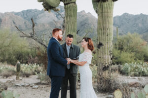 couple during ceremony holding hands among saguaro cacti